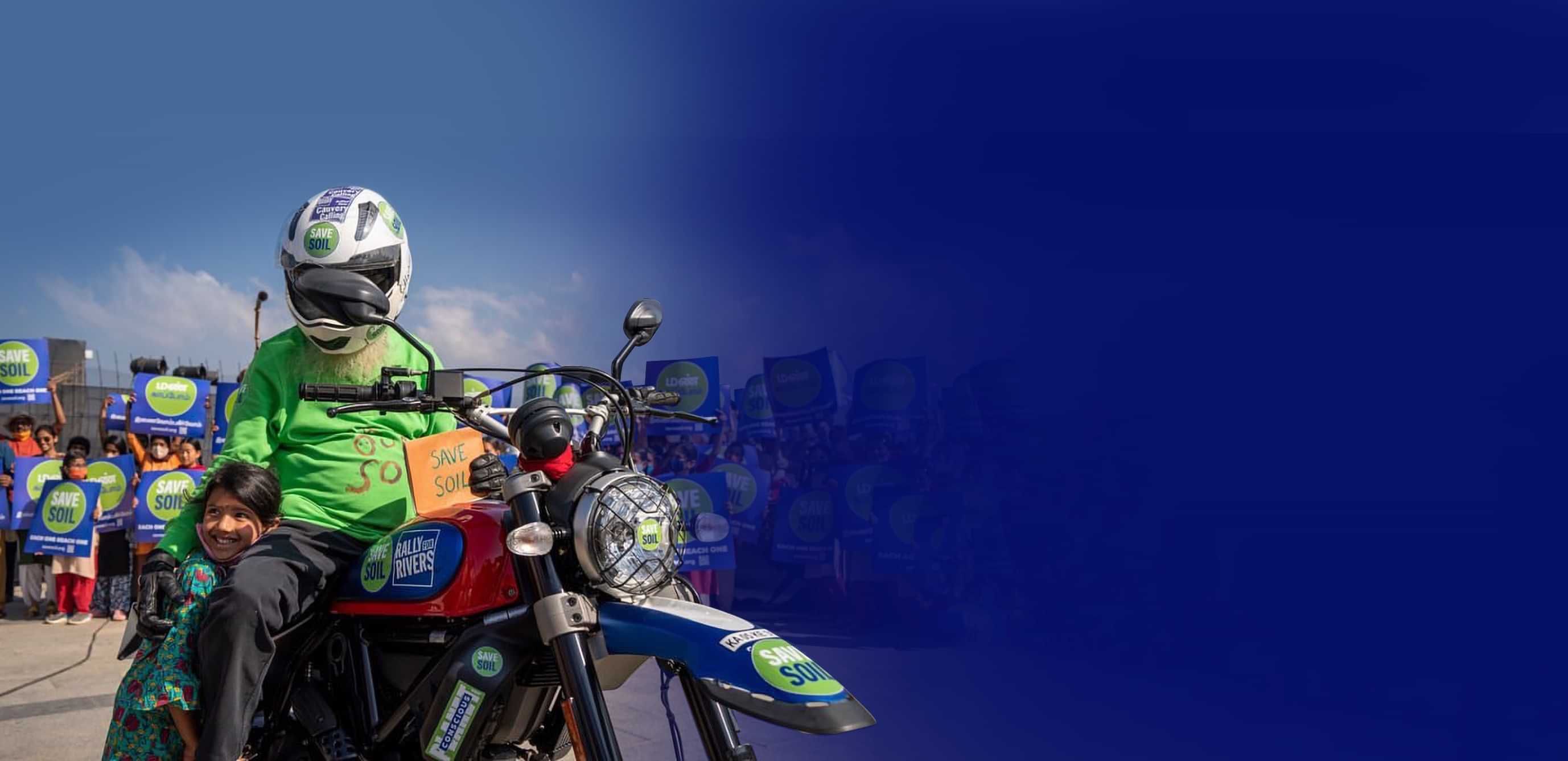 Sadhguru on motorcycle with Save Soil sign, alongside child
